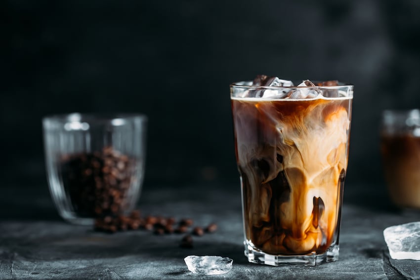 Milk-being-poured-into-iced-coffee-on-a-dark-table.jpg