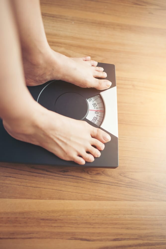 Woman-feet-standing-on-weight-scale-on-wooden-background.jpg